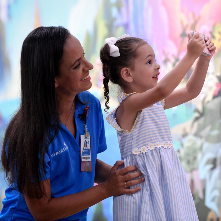 A smiling female nurse engaging with a little girl