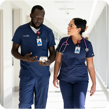 A male and a female nursing professional walking in a hospital corridor
