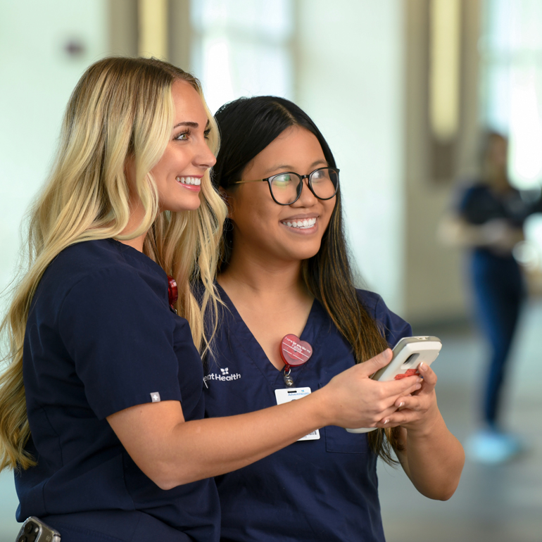 Two smiling female nursing professionals collaborating in a hospital setting