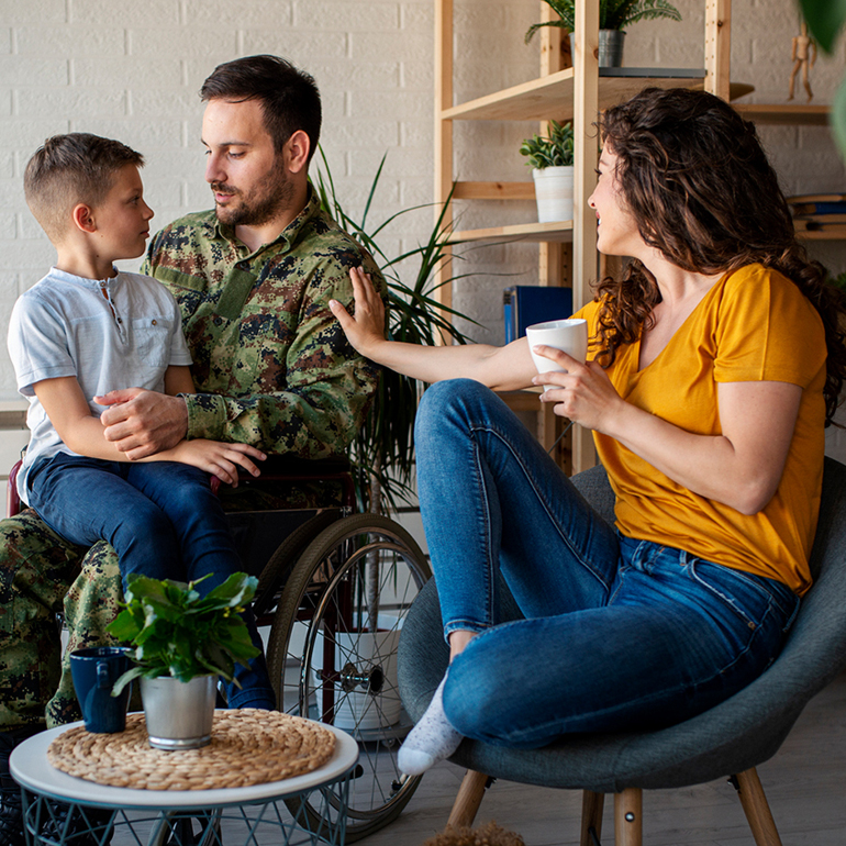 A mother and father at home with their son sitting on the father's lap