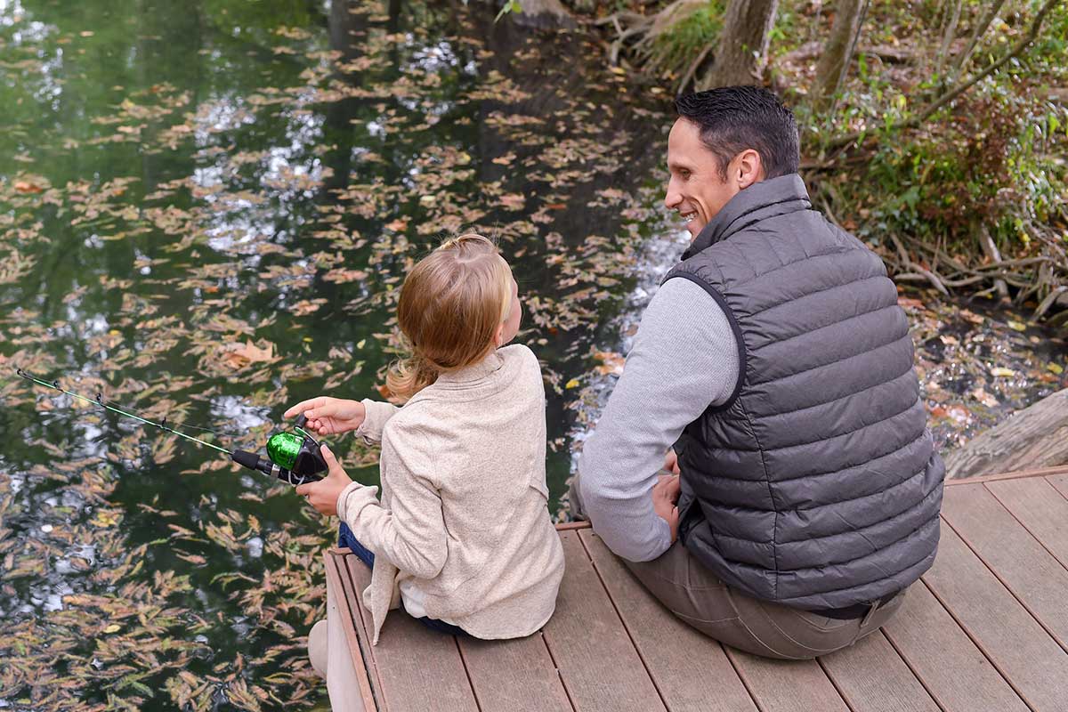 A father and daughter sitting on a pier while fishing