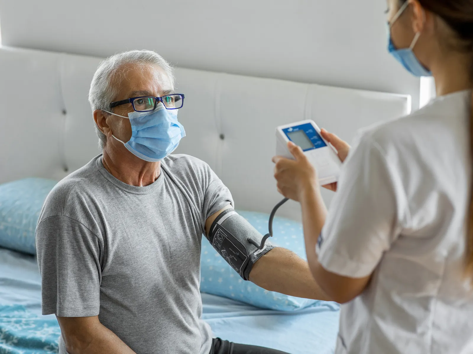 A home health nurse takes a patient's blood pressure.