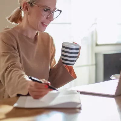 Woman sitting at her laptop and holding a coffee cup