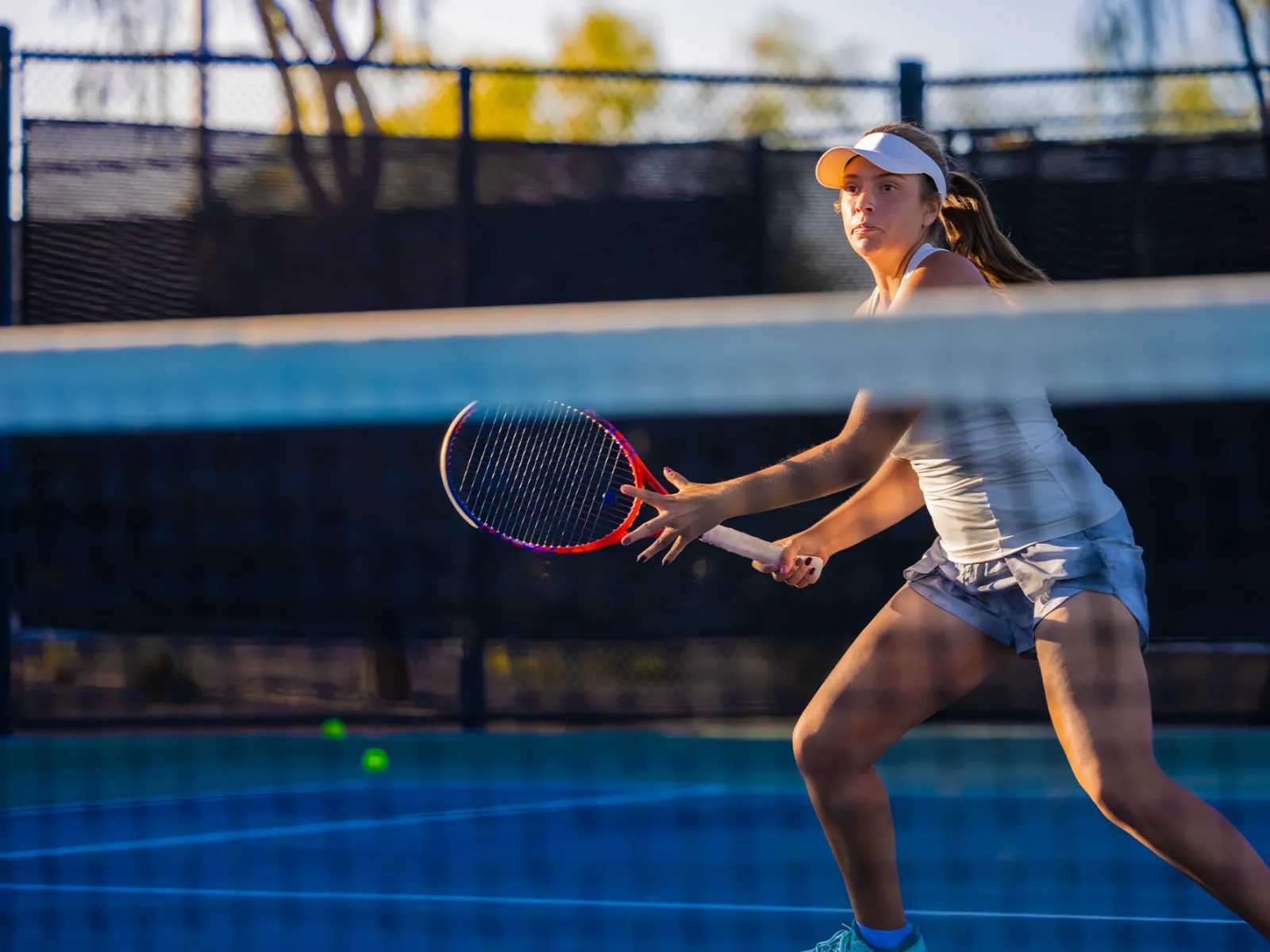 A Woman Playing Tennis Looks Across the Tennis Court as She Prepares to Return a Voley.