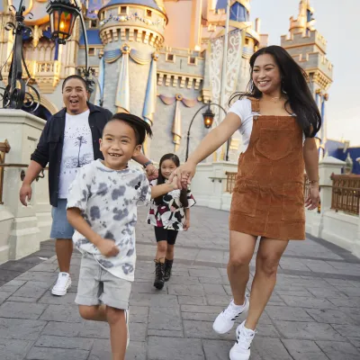 Family running in front of Castle at Walt Disney World®
