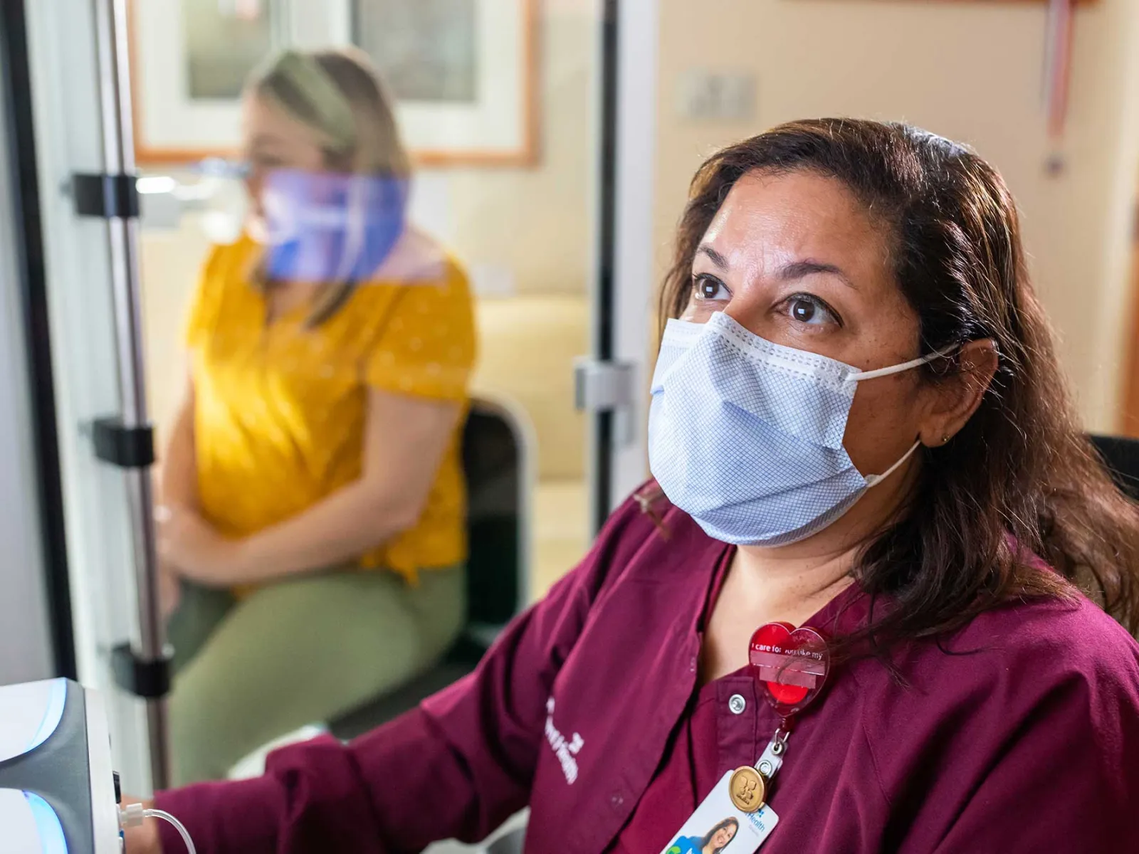 An AdventHealth employee on the computer while helping a patient.