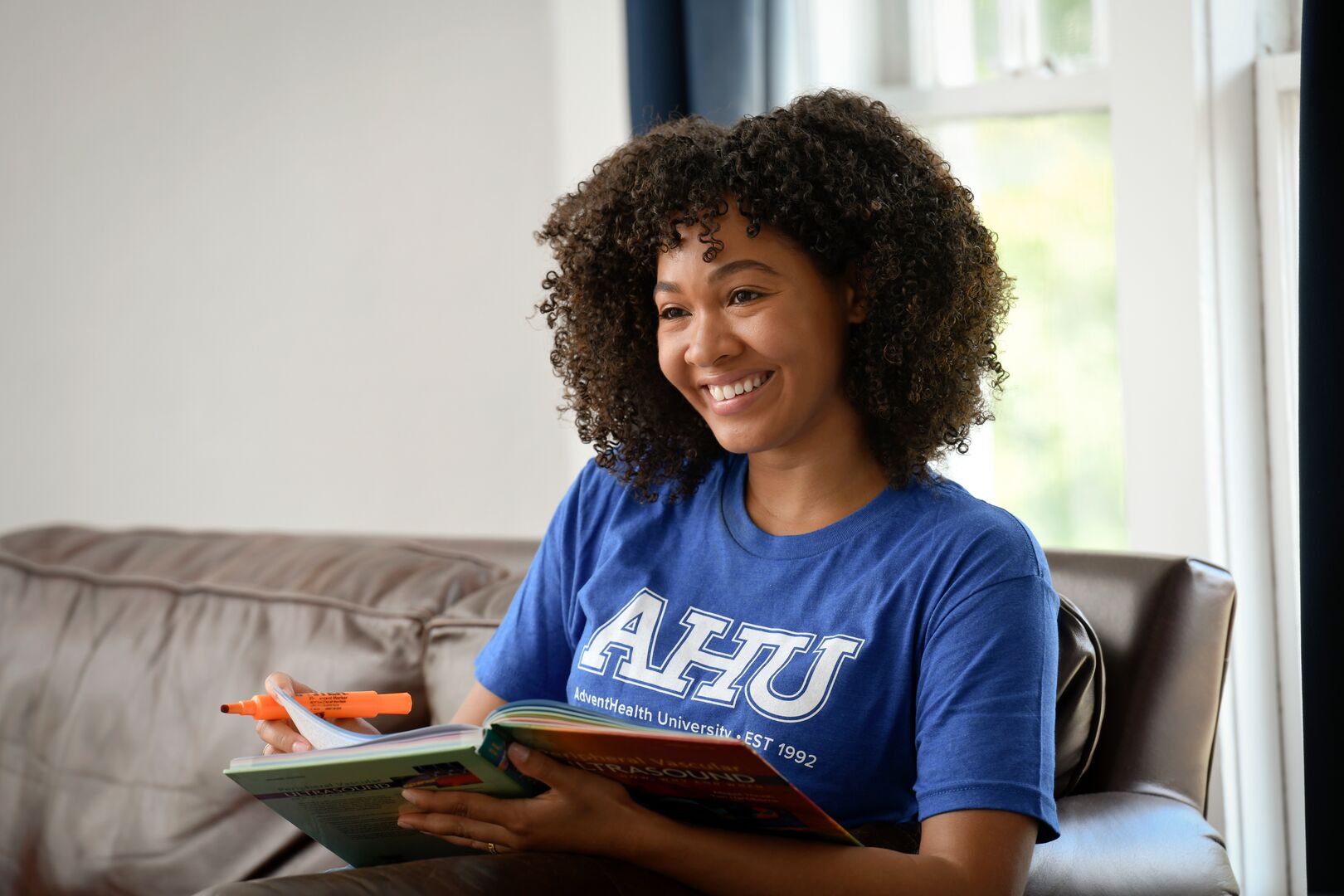 Woman reading and taking notes on a couch.