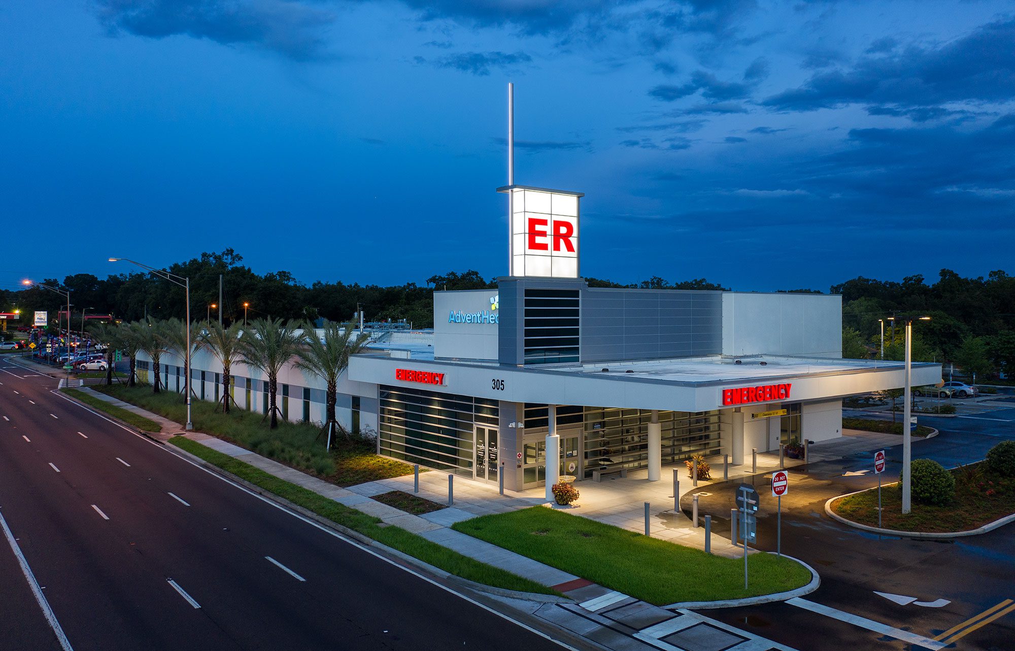 AdventHealth Brandon emergency department exterior at dusk with illuminated ER signage and a roadway in the foreground.