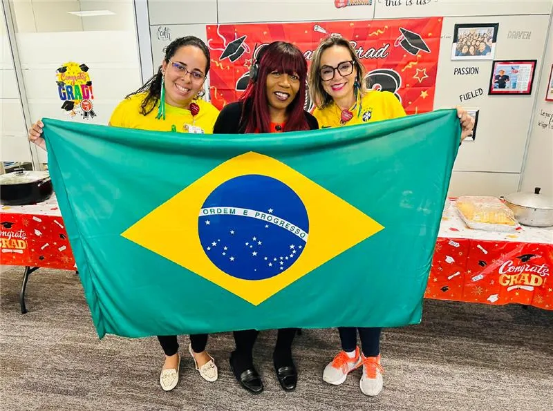 AdventHealth team members holding a Brazilian flag during a Transcultural Assimilation Program event.
